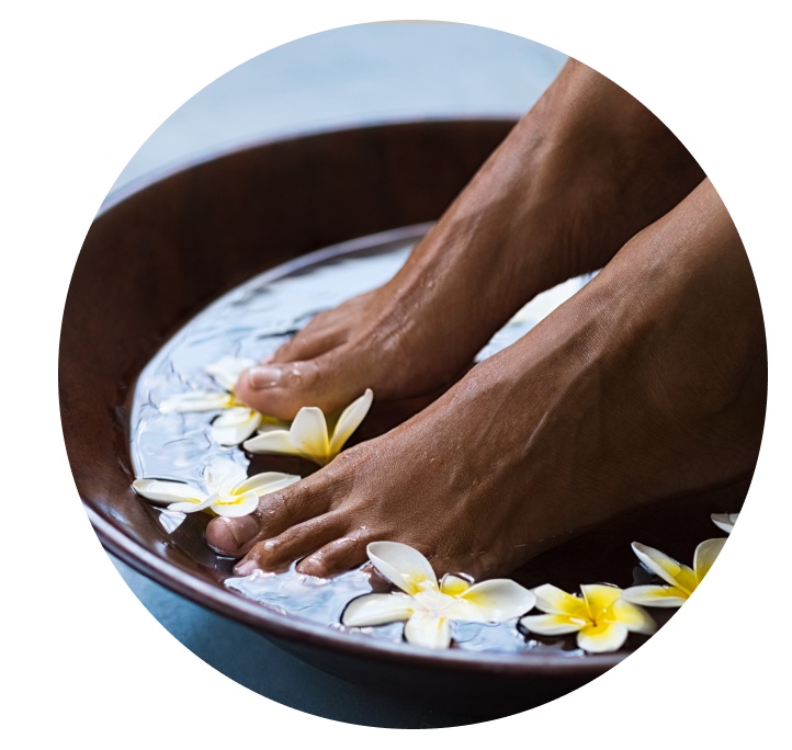 Feet soaking in a spa bowl with flowers